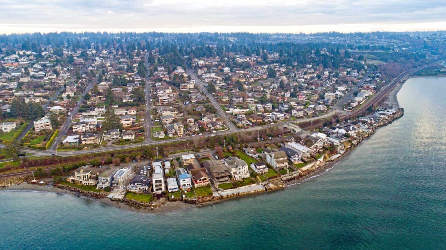 Aerial view of Shoreline, Washington, showing a mix of forested areas, suburban neighborhoods, and roads with Mount Rainier visible in the background under a clear blue sky.